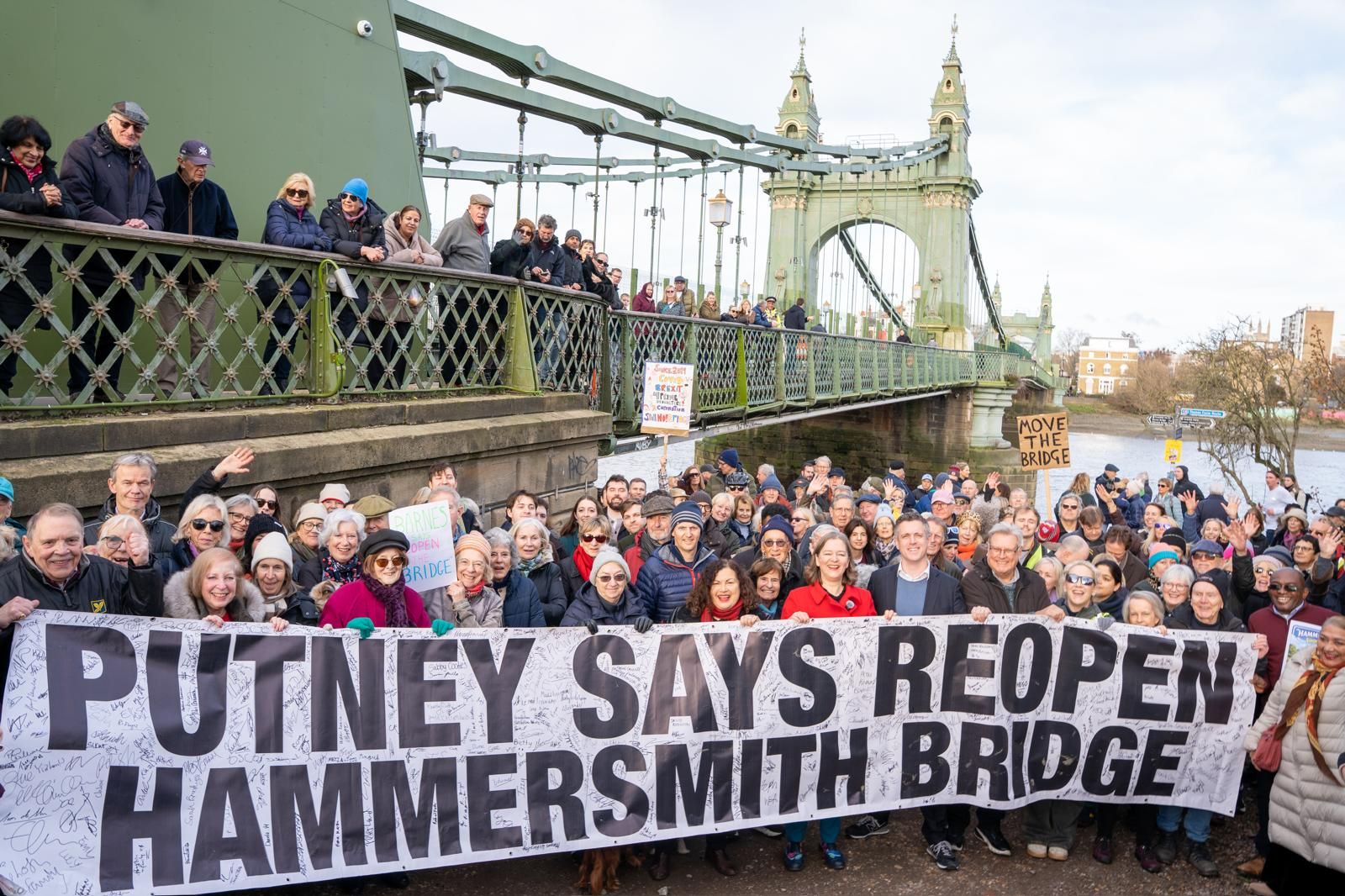 Fleur with hundreds of people in front of banner saying Putney says reopen Hammersmith Bridge